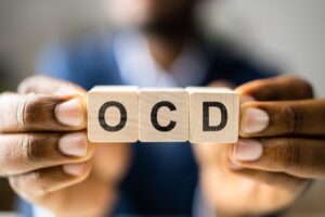 man holding blocks spelling OCD