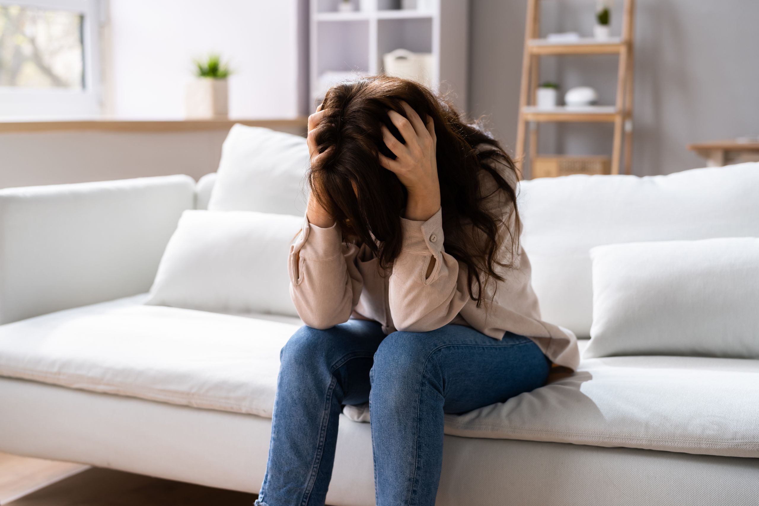 woman sitting on the couch holding her head struggling with ocd in georgia 