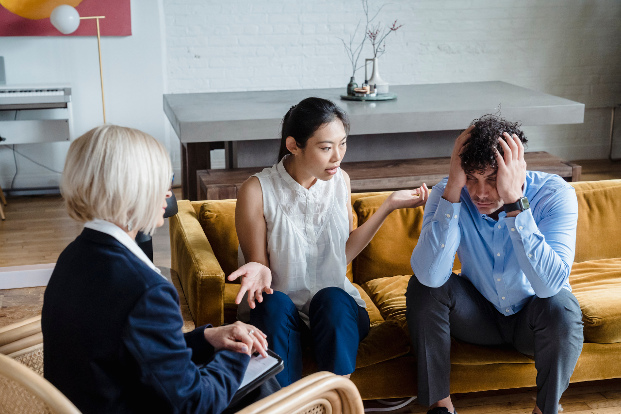 wife sitting with her husband struggling with alcoholism while therapist tells her what is al-anon