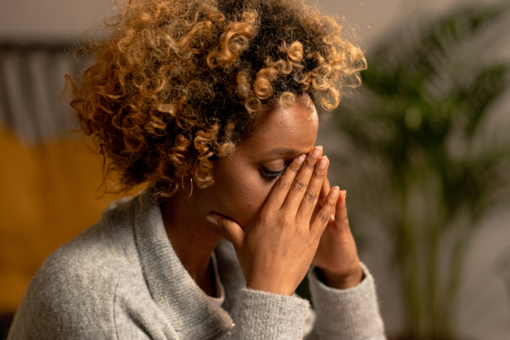 woman bent over holding her head showing 7 signs of high-functioning anxiety